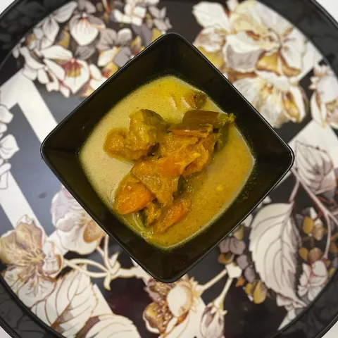 Sri Lankan pumpkin and carrot curry in a square black bowl on a floral serving tray